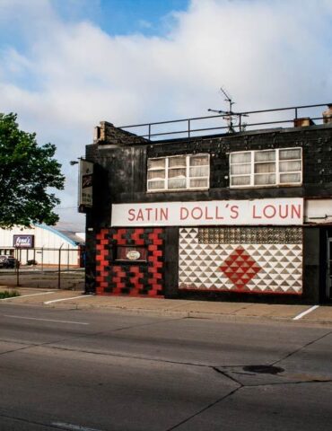 On the outside, the black-painted brick and checkered patterns of red, black, and white could leave someone dizzied, but the interior of Satin Doll’s Lounge did the opposite. Opened in 1977, the legendary jazz club owned by Minnette D. Wilson, known as “Satin Doll,” was a safe, invite-only haven in the heart of the city, located between 23rd and 24th Street on West Fond Du Lac Avenue. Described as elegant, and a beautiful dancer, Wilson, performed with legendary musician Duke Ellington and others. Wilson was Ellington’s muse for the hit song “Satin Doll” sung by Ella Fitzgerald. Wilson brought her personality to lounge, the inside was adorned with photos of Wilson and Duke Ellington, Milwaukee Police department patches, and stuffed animals. The downstairs party room was dedicated to Ellington and included a jukebox filled with his music. Creating Space in a Segregated City When Black musicians were still being discriminated against and not allowed in downtown venues, Satin Doll’s Lounge was a haven to escape to. Attracting both local and national talent, the lounge provided a place for Black musicians to perform in front of inclusive, integrated audiences. Often staying open until the sun came up, the lounge has been described at a non-rowdy place that had a nice social atmosphere. A sign on the door read, “You must be 38 years old or older to enter.” Due to its reputation for being safe and fun, and Wilson, having many connections with the Milwaukee Police Department, Satin Doll’s Lounge, made Milwaukee a true jazz destination for many. By the time of her death at age 79 in 2017, Satin Doll’s Lounge was closed, but Wilson left a rich legacy that continues to inspire today. Preserving Satin Doll’s History Many were able to experience what Satin Doll’s was firsthand, but for those who haven’t, there are groups working to preserve the history not only of the lounge, but also, the impact and contributions of Minnette Wilson to Milwaukee’s jazz scene. The Wisconsin Black Historical Society has documented and celebrated Wilson’s life and work. They have preserved photographs, posters, recordings of performances, and more to serve as a connection to the past and hopefully inspire the next generation. Satin Doll’s Lounge legacy remains strong today and demonstrates a beacon of hope and resiliency, that should be honored. Satin Doll Lounge