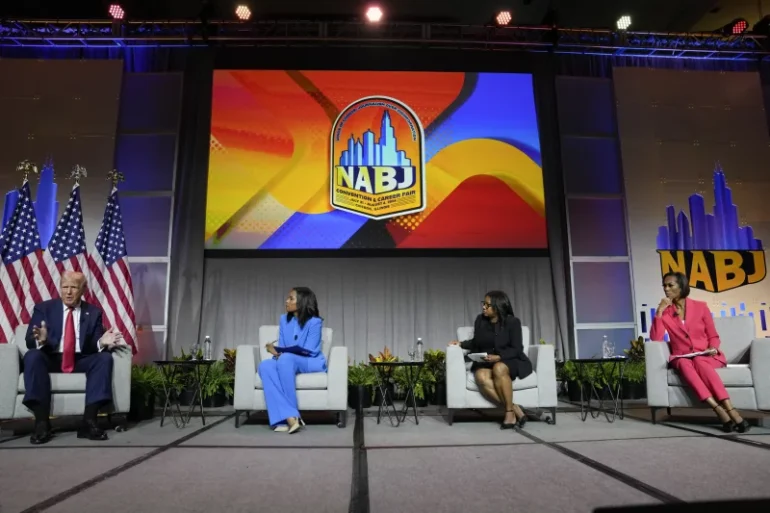 Former President Donald Trump appears on a panel at NABJ on Wednesday in Chicago. From left, ABC's Rachel Scott, Semafor's Kadia Goba and FOX News' Harris Faulkner moderated the event. Charles Rex Arbogast/AP