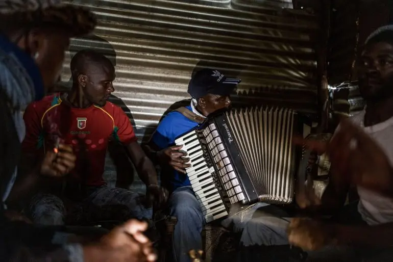 A man plays an accordion as people gather at a local tavern, also known as shabeen, in Semonkong.